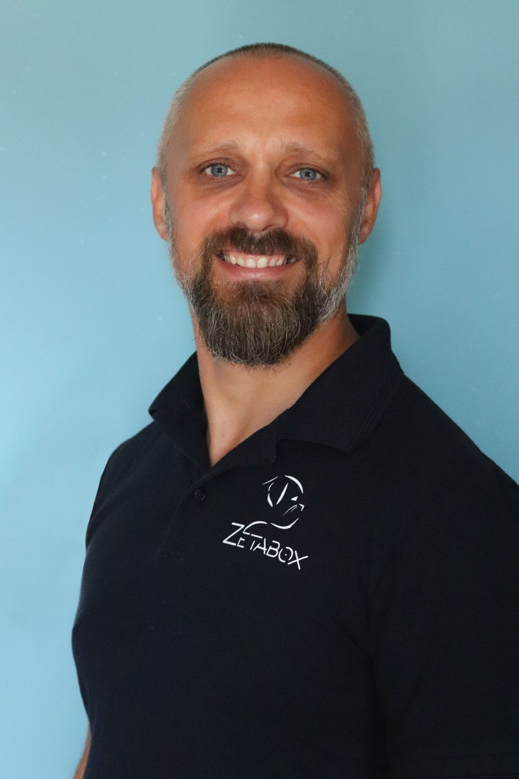 Čovjek sa tamno plavom majicom logom Zetabox i sa osmjehom